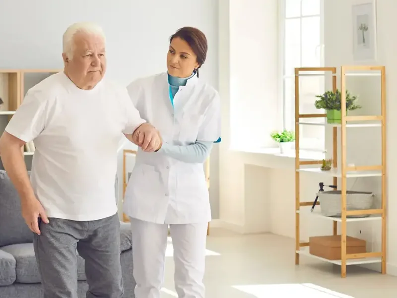 A therapist steadying an older man as he walks