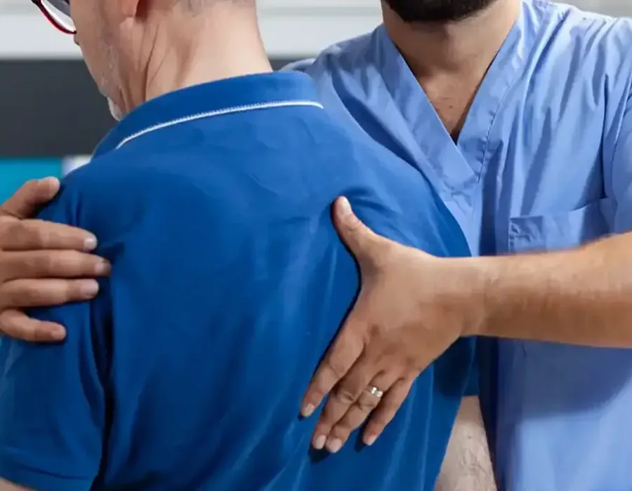 A therapist assessing a patient&rsquo;s shoulder joint by hand