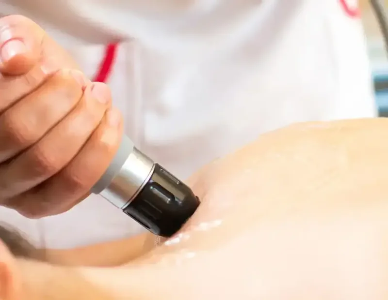 A shockwave therapy applicator being used on a patient&rsquo;s leg