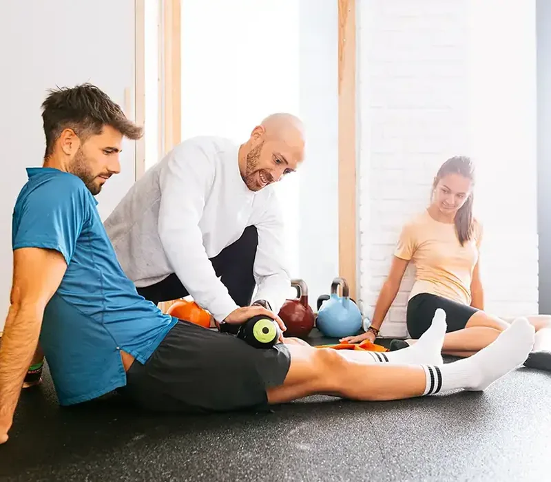 A therapist working with an athlete on the floor during sports rehab