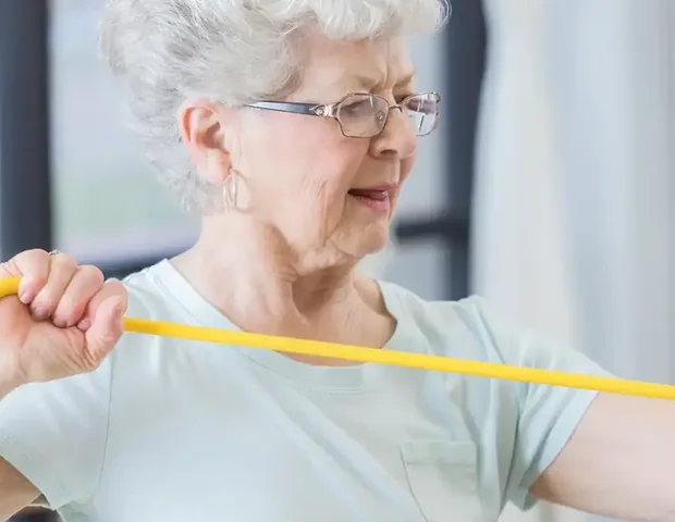 An older patient working with a resistance band during her session